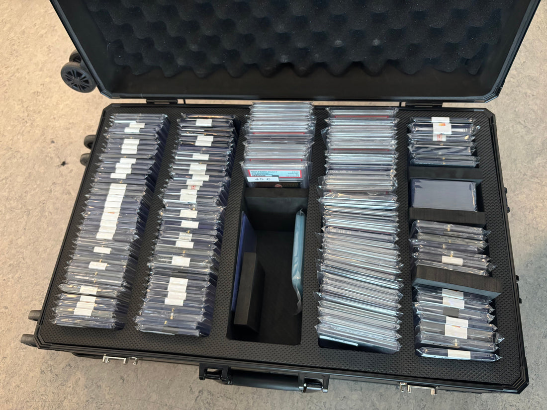 Open card case packed with toploaders and slabs, ready for a card show